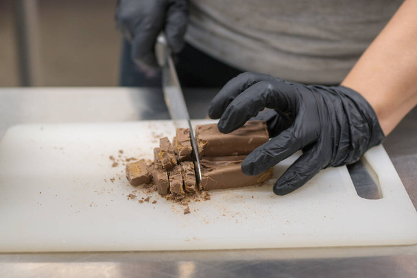 chef-kok snijden chocolade fudge snoep voor cheesecake voorbereiding close-up shots, cateraar professionele keuken - Foto, afbeelding