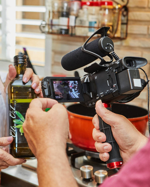 Están filmando video de la cocina, botella de aceite de oliva en las manos del cocinero. - Foto, imagen