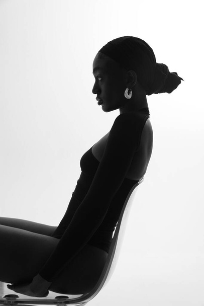 Vertical portrait of young African woman posing on white wall. Black and white. High quality photo. - Foto, afbeelding