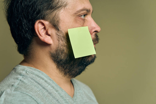 Retrato facial de um homem com uma barba no perfil e coberto com adesivos de papel em branco - Foto, Imagem