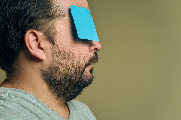 Facial portrait of a man with a beard in profile and covered with blank paper stickers - Photo, Image