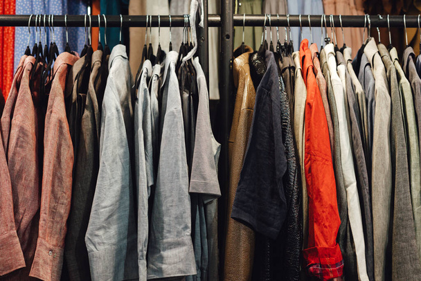 Auswahl an modischen Hemden in verschiedenen Farben auf Metallbügeln in einem Einzelhandelsgeschäft. Reduzieren Recycling-Konzept. Horizontales Foto. - Foto, Bild