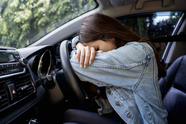 Ασιάτισσα στρεσαρισμένη ή κουρασμένη στο αυτοκίνητο ξαπλωμένη στο τιμόνι - Φωτογραφία, εικόνα
