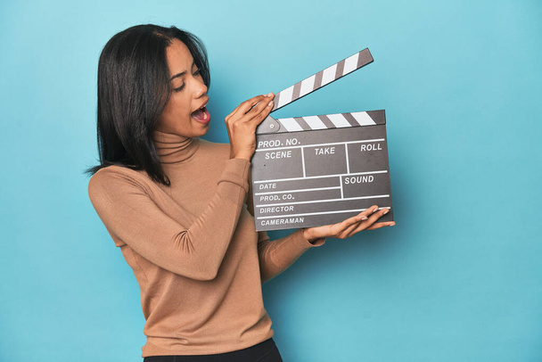 Filipina with film clapperboard on blue studio background - Photo, Image