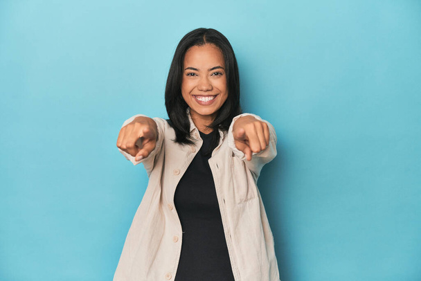 Filipina young woman on blue studio cheerful smiles pointing to front. - Photo, Image