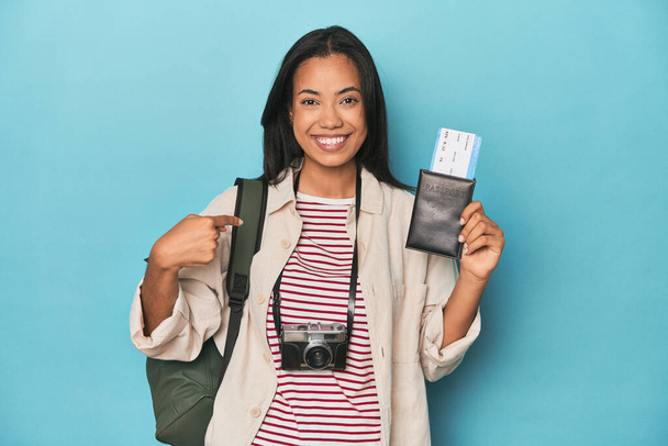 Филиппина с камерой, билеты, рюкзак на синий человек указывая вручную на рубашку копировать пространство, гордый и уверенный - Фото, изображение