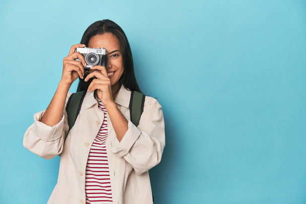 Joven Filipina capturando momentos con la cámara en un fondo de estudio azul - Foto, imagen