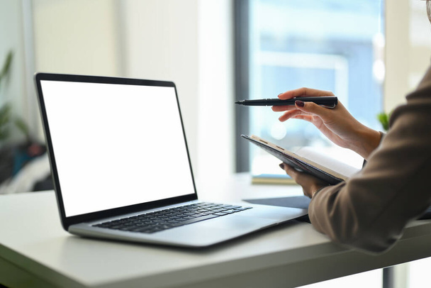 Невпізнавана бізнес-леді тримає ноутбук і використовує ноутбук на офісному столі. Порожній екран для текстового повідомлення реклами. - Фото, зображення
