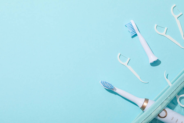 Brosses à dents électriques et fil dentaire sur fond bleu, espace pour le texte - Photo, image