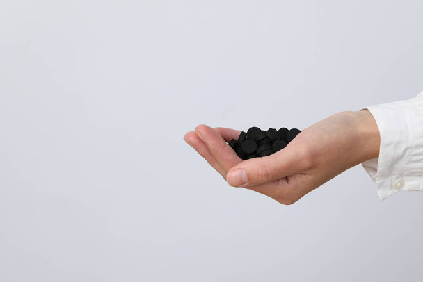 Tablets of activated carbon in the hands of a doctor on a light background - Photo, Image