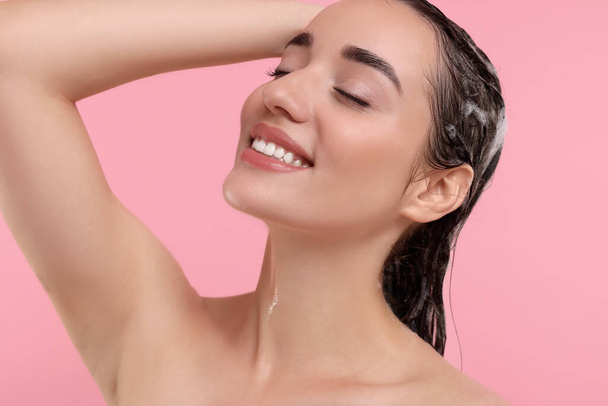 Portrait of beautiful happy woman washing hair on pink background - Foto, afbeelding