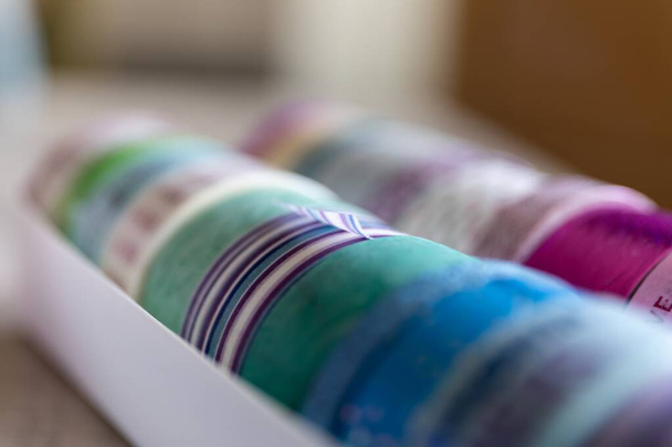 Renkli washi bantlarının bir kutuda farklı desenler ve renklerde yakın çekimi. Dekoratif rulo bir posta kartı veya hediye kartı süslemek için kullanıma hazır, ya da iç tasarım için, duvardaki gibi.. - Fotoğraf, Görsel