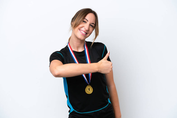 Mujer joven caucásica con medallas aisladas sobre fondo blanco dando un gesto hacia arriba pulgares - Foto, Imagen