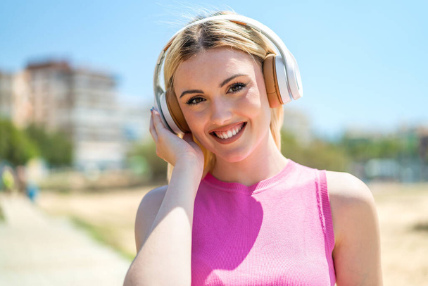 jong mooi blond vrouw op buiten luisteren muziek - Foto, afbeelding