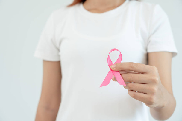 Γυναίκα κατέχει ροζ κορδέλα ευαισθητοποίησης για τον καρκίνο του μαστού. Γυναικεία συνείδηση ελέγχου υγείας. Παγκόσμια Ημέρα της Γυναίκας και Ημέρα του Καρκίνου. σημάδι του καρκίνου, Συμβολικό, υγειονομική περίθαλψη, υποστήριξη ασθενών, έγκαιρη διάγνωση - Φωτογραφία, εικόνα