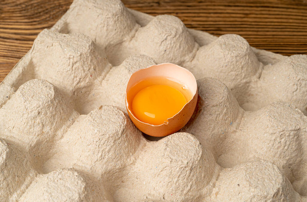 Un uovo di pollo rotto, uova rotte in confezione di cartone, contenitore di uova fresche di gallina marrone con cibo biologico solitario Primo piano - Foto, immagini