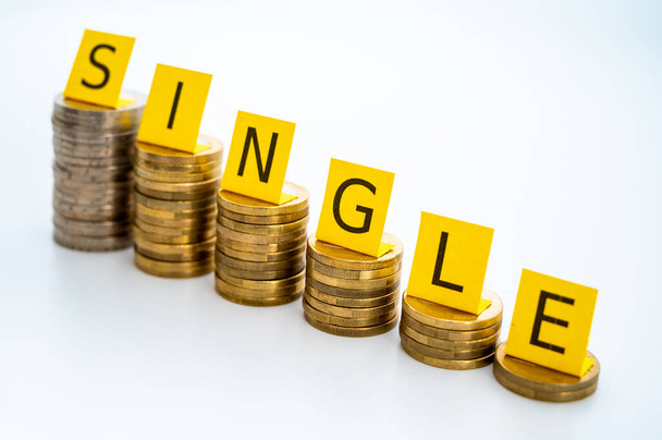 Stacks of coins with Single text. Economic conditions of single people, higher expenses of single people. - Photo, Image