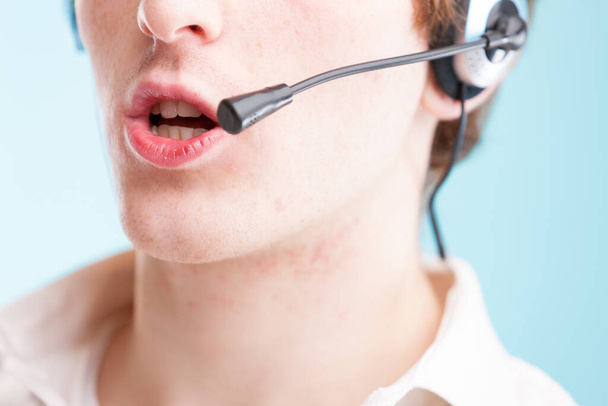 When you think 'contact us," picture this: close-up of a young man's lips to neck, speaking into a headset. Wearing a white shirt, representing customer assistance, but hailing from an underprivileged - Photo, Image