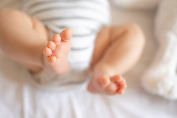De kleine voet van een pasgeboren baby. Zachte voeten van een pasgeborene in een witte deken. Sluiten van tenen en voeten van een pasgeborene. Macrofotografie. - Foto, afbeelding
