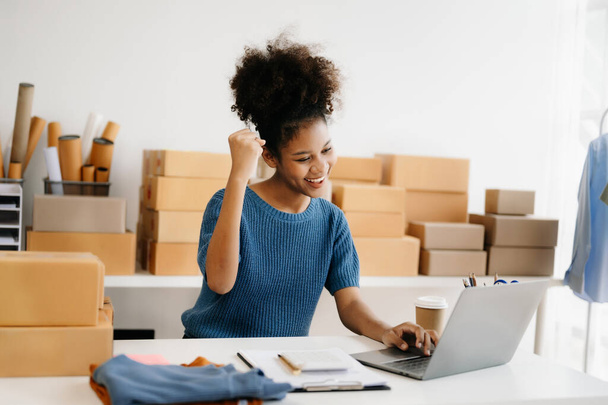 Young African business owner woman prepare parcel box and standing check online orders for deliver to customer on laptop, Shopping Online concept - Photo, image