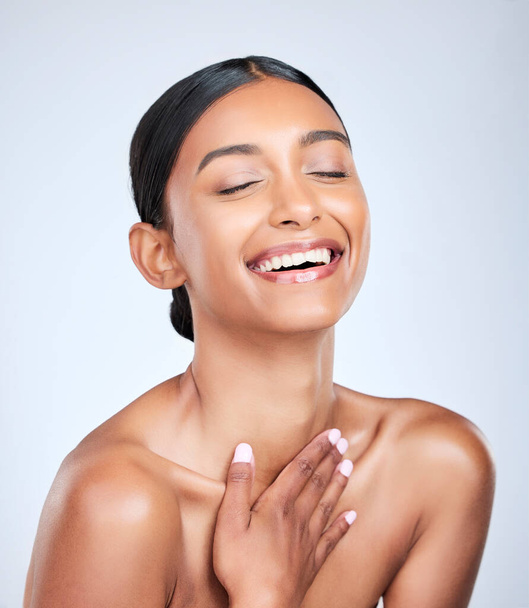 Face, skincare and smile with a woman laughing for health, wellness or dermatology in studio on white background. Skincare. funny and a happy young model feeling satisfaction at her cosmetic routine. - Φωτογραφία, εικόνα