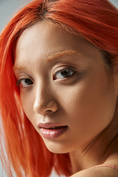 közelről ázsiai fiatal nő természetes smink és vörös haj nézi kamera, puha bőr - Fotó, kép