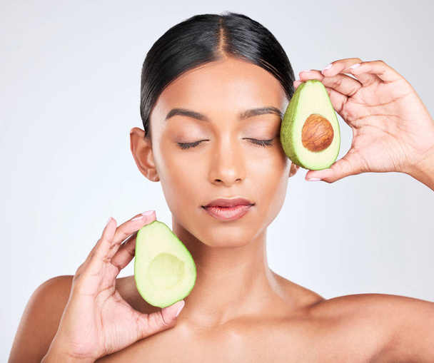 Face, avocado and woman with natural beauty, facial and eco friendly skincare isolated on white background. Wellness, dermatology and vegan cosmetics product with glow, shine and green in studio. - Photo, Image
