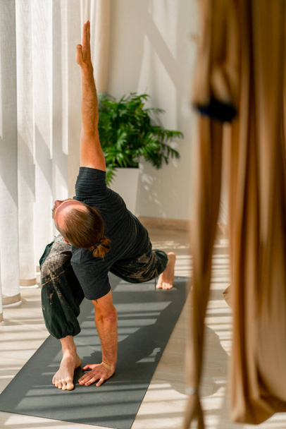 hombre resistente levanta las manos y hace un estiramiento de todo el cuerpo realiza elementos de yoga - Foto, imagen