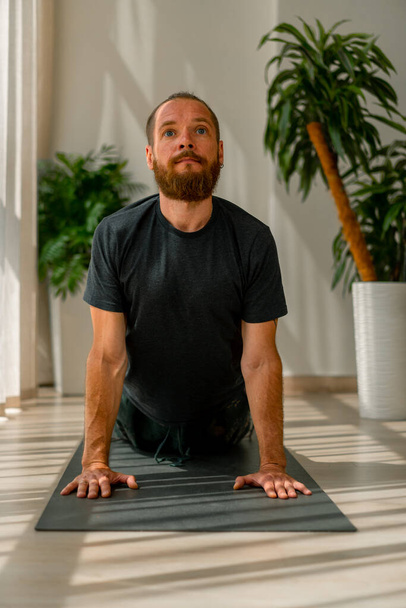 volwassen man met een baard doen stretching en rug gezondheid liggend op vloer sport actieve levensstijl - Foto, afbeelding