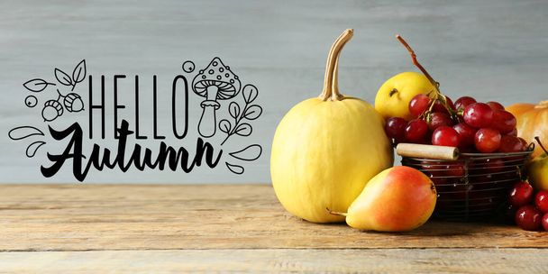 Fresh fruits with pumpkin and text HELLO AUTUMN on wooden background - Photo, Image