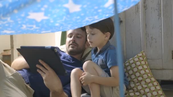 Father using digital tablet with his son - Felvétel, videó