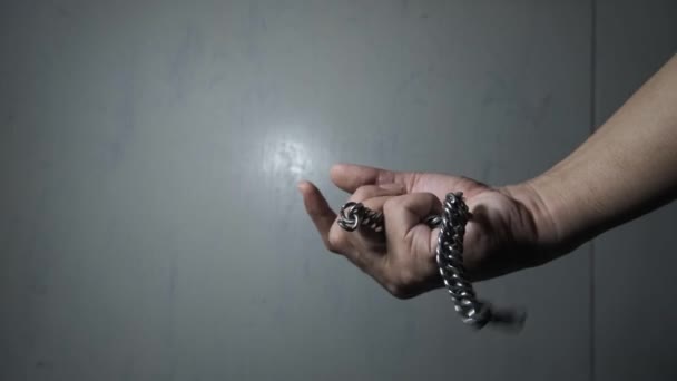 4k footage. Anger-inducing memories. An Asian man dressed in black catches a chain-shaped bracelet that fell onto his hand and grips it tightly. - Footage, Video