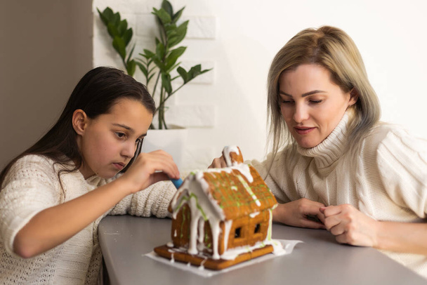 Noel arifesinde ailenin zencefilli kurabiye evini dekore etmesi. - Fotoğraf, Görsel