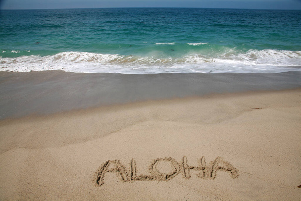 Слово ALOHA, написане на піску на пляжі на Гаваях. - Фото, зображення