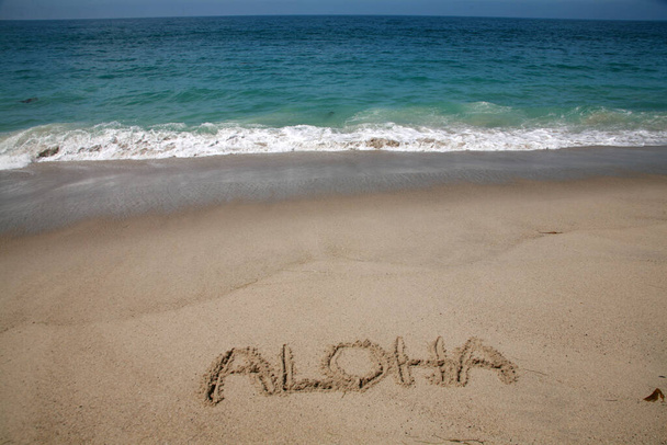 Слово ALOHA, написане на піску на пляжі на Гаваях. - Фото, зображення