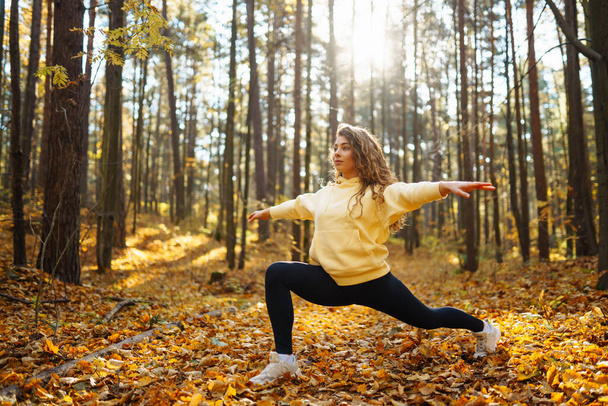 Piękna kobieta praktykuje jogę w jesiennym lesie. Koncepcja stylu życia i medytacji. - Zdjęcie, obraz
