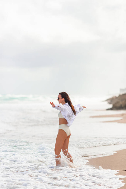 Νεαρή γυναίκα στην παραλία στις καλοκαιρινές διακοπές - Φωτογραφία, εικόνα