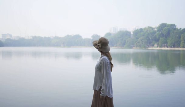 Mutlu Asyalı Vietnamlı kadın portresi Hanoi şehir merkezinde göl ve nehirle halka açık park bahçesinde seyahat ediyor. Şehir, Vietnam. İnsan yaşam tarzı. - Fotoğraf, Görsel