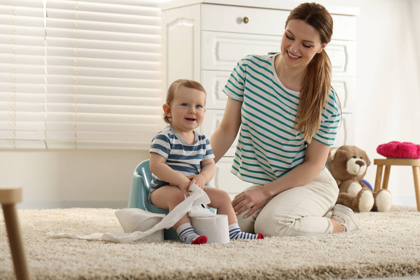 Mother training her child to sit on baby potty indoors. Space for text - Photo, image