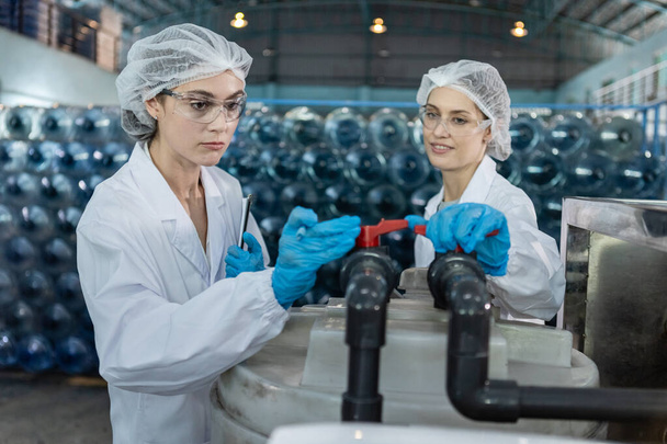 Vrouwelijke werknemer controleren kwaliteit klep On en Off water productielijn van de fabriek. beheersysteem voor het vullen van water in flessen. Industrie van drinkwaterproducten. - Foto, afbeelding