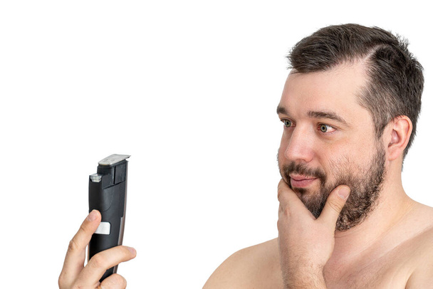 незахищений молодий чоловік ідеальної шкіри тримає електричну бритву гоління, ізольовано. Концепція косметичних процедур по догляду за шкірою. Вирощування для сучасної людини. красивий чоловік використовує електричну бритву - Фото, зображення