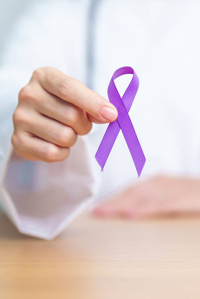 Médecin tenant un ruban violet pour la violence, le pancréas, l'œsophage, le cancer du testicule, la maladie d'Alzheimer, l'épilepsie, le lupus, la sarcoïdose et la fibromyalgie. Mois de sensibilisation et concept de Journée mondiale du cancer - Photo, image