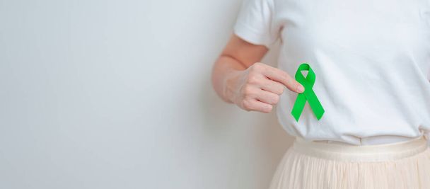 Yeşil kurdeleli karaciğer ağrısı çeken bir kadın. Karaciğer kanseri farkındalık ayı, Tümör, Sarılık, Virüs Hepatiti, Siroz, Hata, Büyüme, Hepatik Ensefalopati ve Sağlık Konsepti - Fotoğraf, Görsel