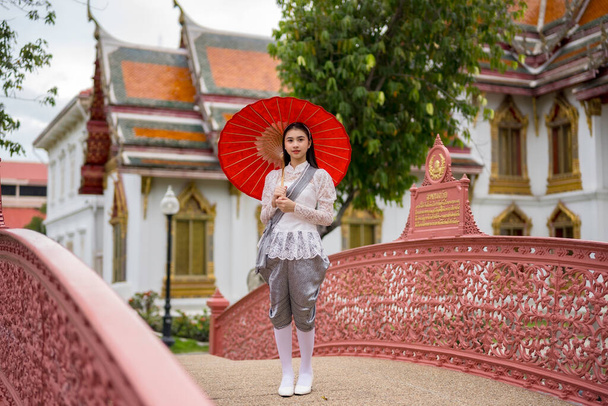 Porträt einer schönen jungen Frau in thailändischer Rattanakosin-Nationaltracht in einem Tempel, der nach thailändischer Kunst in Thailand erbaut wurde - Foto, Bild