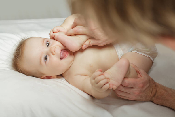 Joyeux bébé tenant ses pieds tandis que son père fait un massage du ventre et du corps pour lui - Photo, image