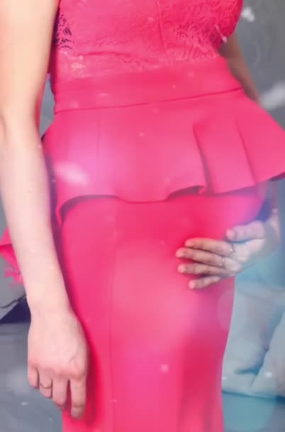 En cámara lenta. Película. Vídeo. Embarazo. Una chica embarazada con un vestido rosa está parada en el reloj de Año Nuevo. Mujer alegre embarazada tocando el vientre y sonriendo en casa. Espacio libre. Fotografía de maternidad - Imágenes, Vídeo