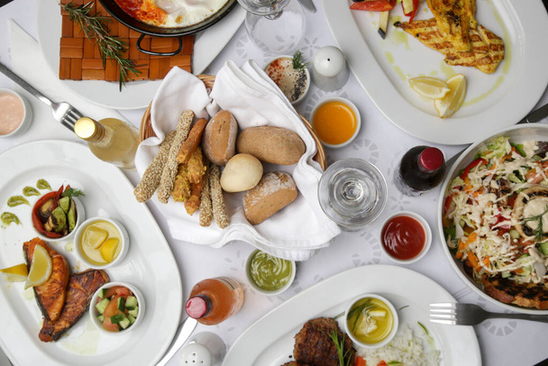 Różne dania kuchni śródziemnomorskiej i wina serwowane na stole restauracyjnym - Zdjęcie, obraz
