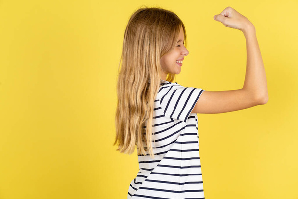 Profile photo of beautiful caucasian teen girl wearing striped T-shirt over yellow background supporting soccer team World Cup 2022 raise fist shouting - Photo, Image