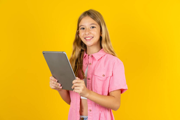 Foto di ragazza ottimista che indossa giacca rosa su sfondo giallo tenere tablet - Foto, immagini