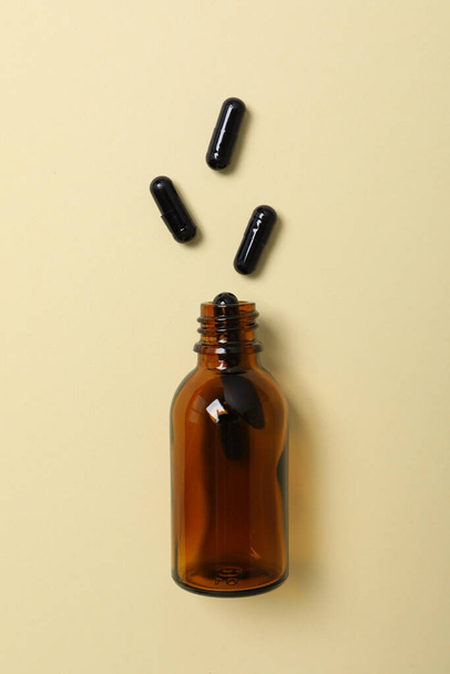 Comprimidos de carvão ativado e uma garrafa de vidro sobre um fundo claro - Foto, Imagem